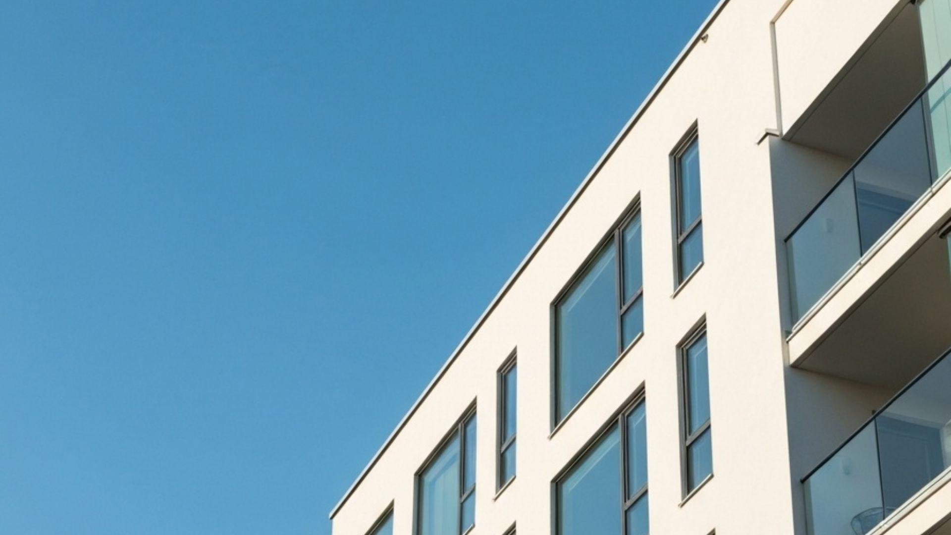 Moderne skandinavisk leilighetsbygg med store rene vinduer mot klar blå himmel