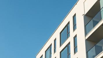 Moderne skandinavisk leilighetsbygg med store rene vinduer mot klar blå himmel