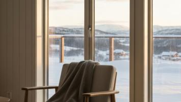 Lun skandinavisk stue med rene vinduer som vender ut mot snødekt norsk landskap